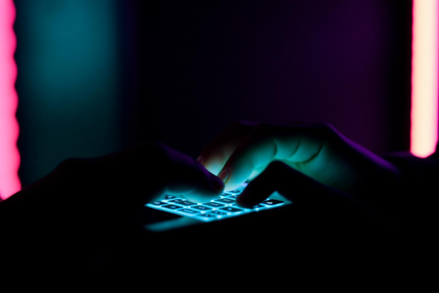 Mão digitando comentário em teclado iluminado
